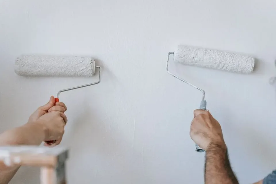 Rouleau appliquant une peinture blanche sur un mur.