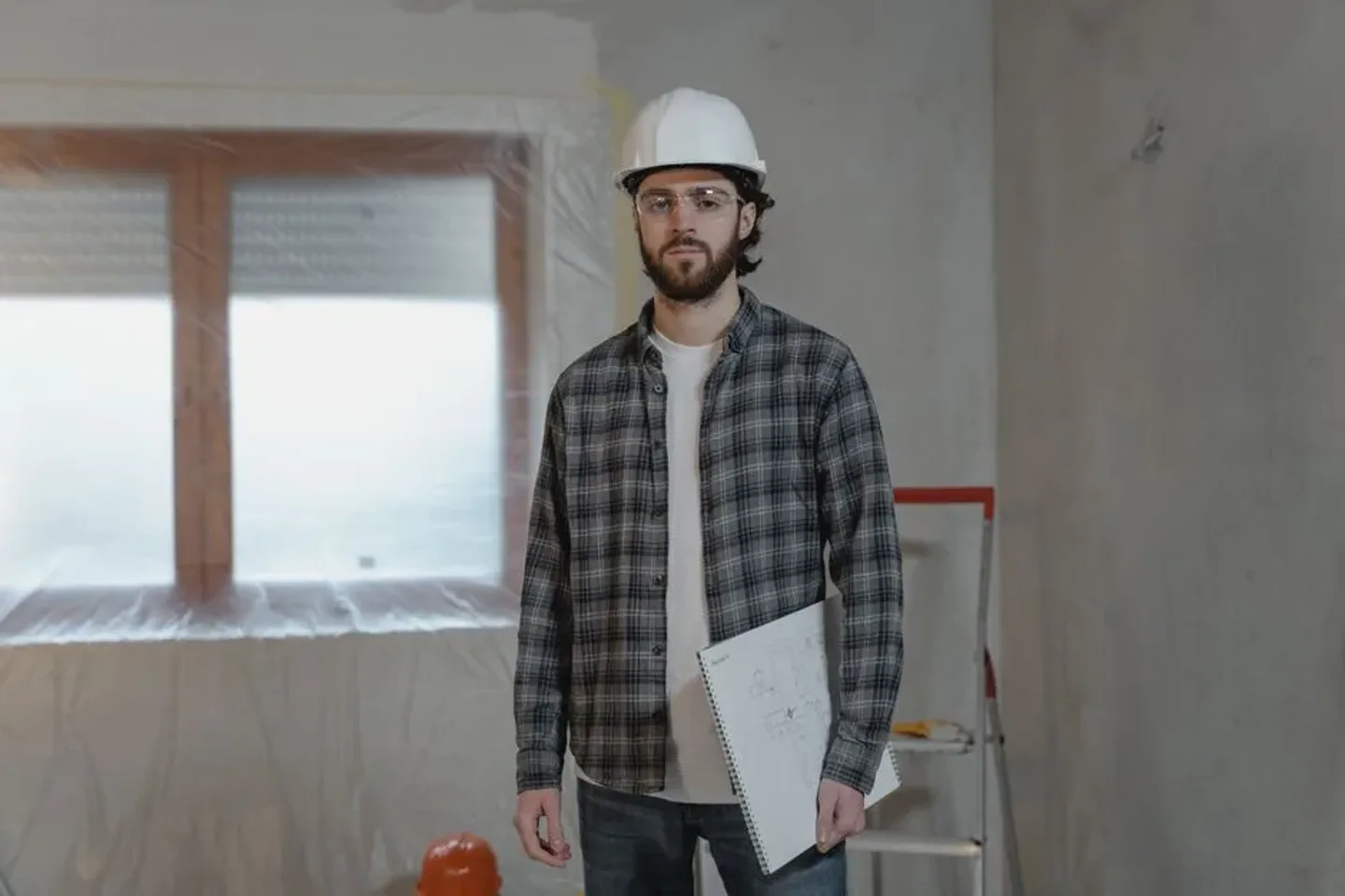 Artisan sur un chantier de rénovation, plans à la main.
