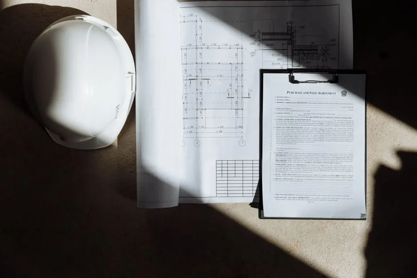 Documents de chantier et casque posés au soleil, préparation d’un projet.