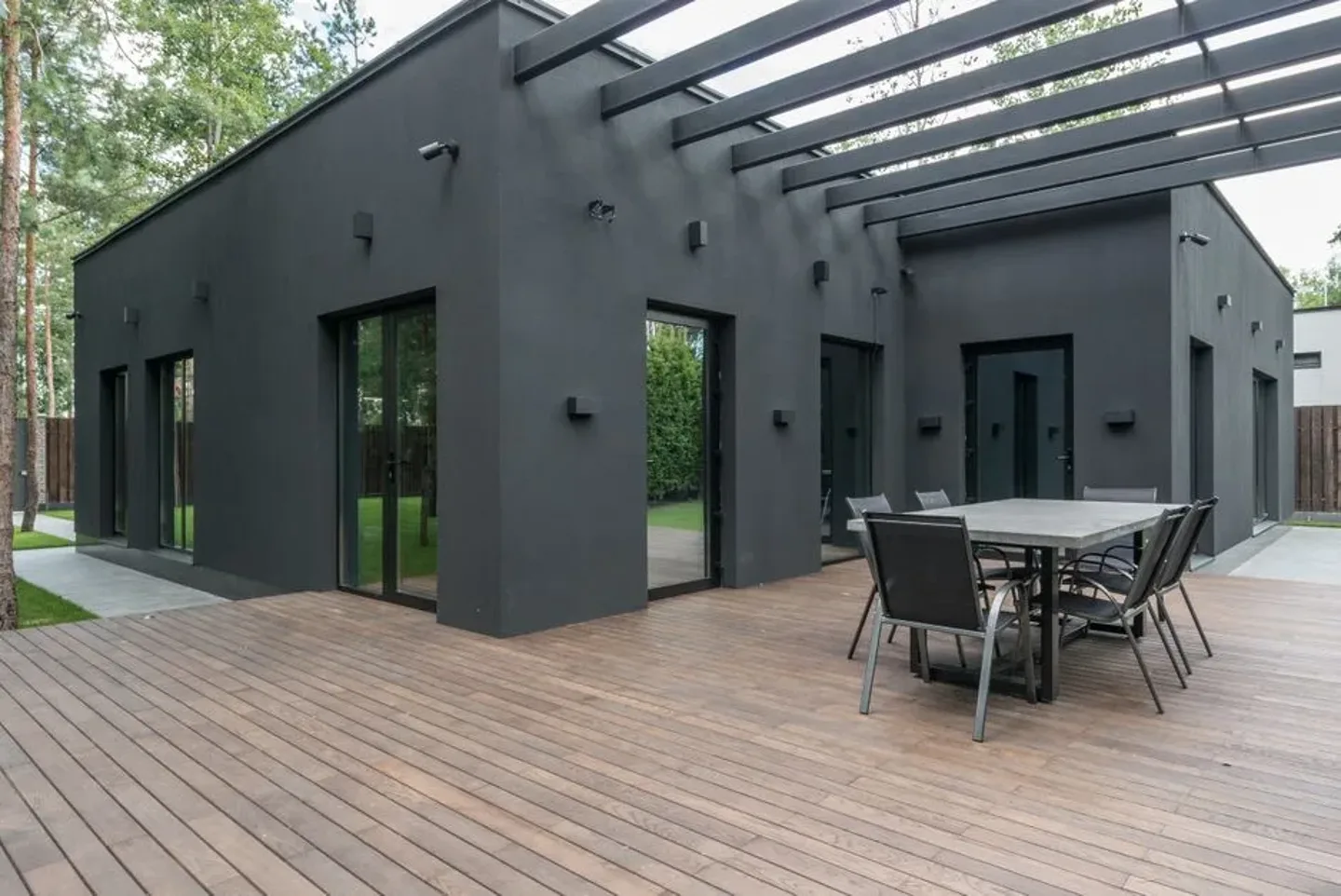 Façade d’une maison avec terrasse en bois ouvrant sur une pelouse.